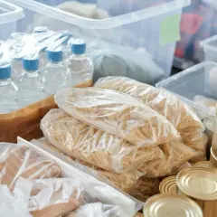 Zapas na kryzys: butelkowana woda, makaron, konserwy i inne produkty spożywcze w plastikowych opakowaniach i puszkach.