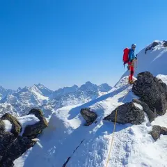 Zimowa wyprawa na Orlą Perć. Dwóch alpinistów wspinających się po ośnieżonych skałach, z widokiem na majestatyczne Tatry.