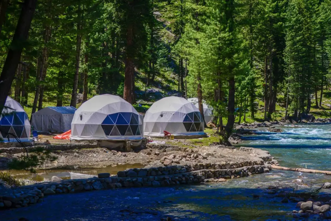 Dome-shaped namioty w lesie nad rzeką to przykład, co to jest glamping. Luksusowy wypoczynek na łonie natury.