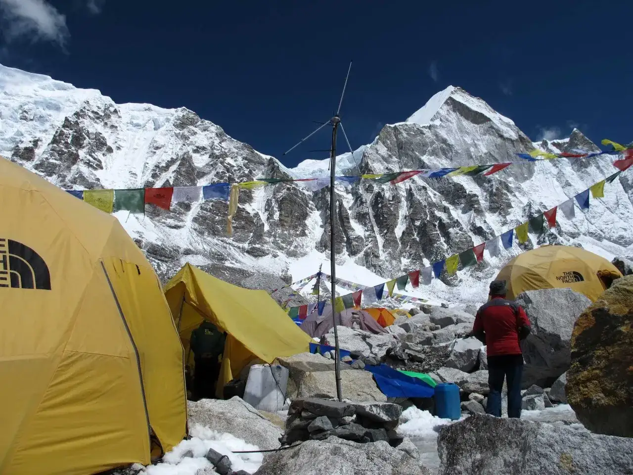 Obóz pod Mount Everest, z namiotami i flagami modlitewnymi. Zastanawiasz się, ile wchodzi się na Mount Everest? To dopiero początek podróży.