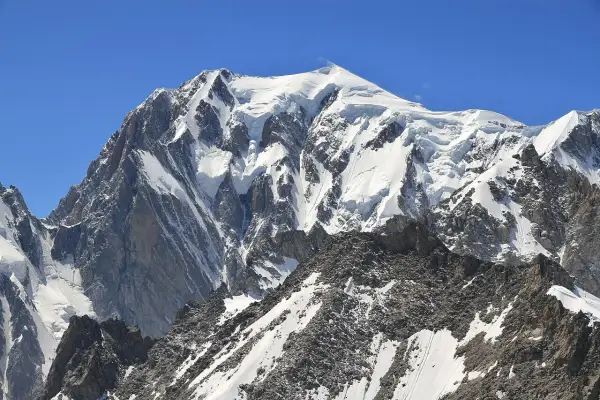 Majestatyczne wejście na Mont Blanc. Śnieżne szczyty i skaliste zbocza pod błękitnym niebem.