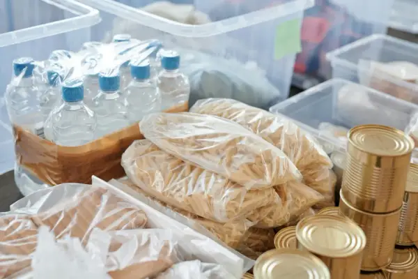 Zapas na kryzys: butelkowana woda, makaron, konserwy i inne produkty spożywcze w plastikowych opakowaniach i puszkach.