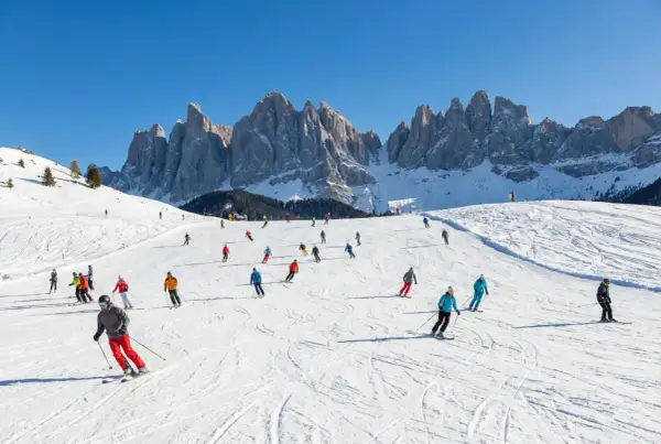 Włochy narty gdzie? Na stoku w Dolomitach, gdzie słońce oświetla ośnieżone szczyty, a narciarze szusują po białych trasach.