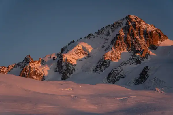 Ośnieżone szczyty Alp oświetlone złotym blaskiem zachodzącego słońca. Widok na trasę Haute Route, gdzie lodowce i skaliste zbocza tworzą majestatyczny krajobraz.