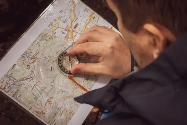 Mężczyzna z kompasem i mapą w Beskidach, przygotowuje się do wyprawy bushcraft a survival.