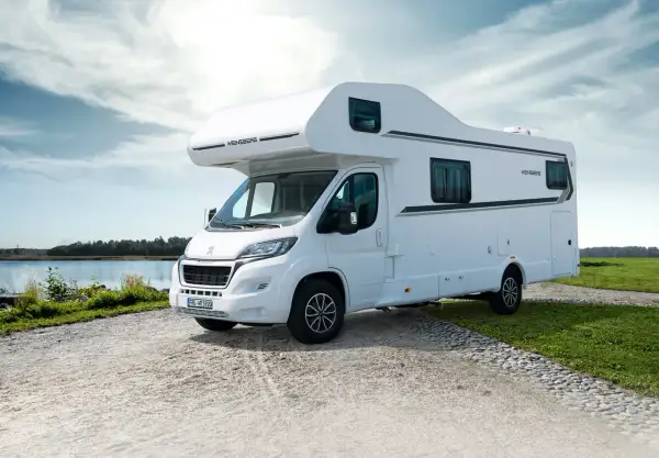 Biały kamper Weinsberg zaparkowany nad jeziorem, gotowy na przygodę. Ten camper to wolność podróżowania.