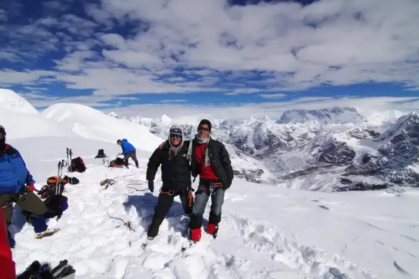 Dwóch alpinistów na śnieżnym szczycie Mera Peak, z zapierającym dech w piersiach widokiem na Himalaje.